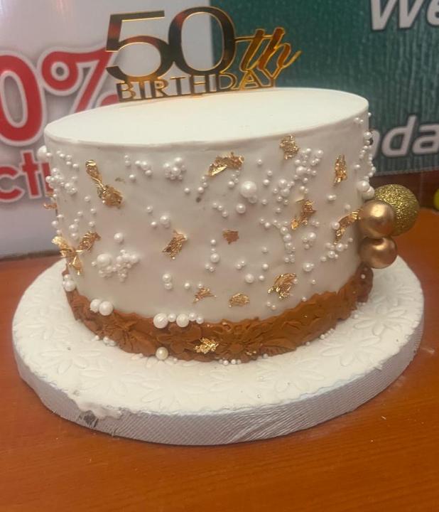 White 50th birthday cake with pearls and gold leaf