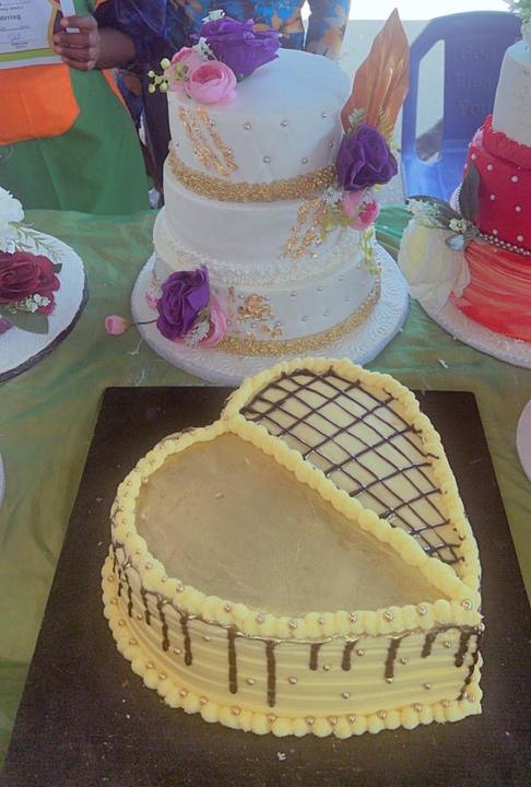 Three-tier white and gold cake beside a heart-shaped cake