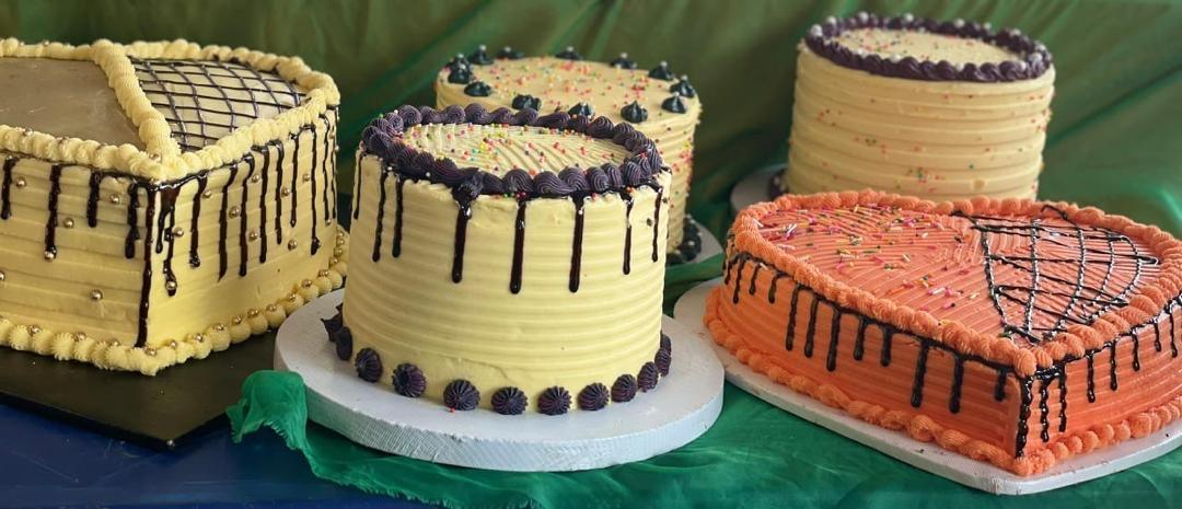 A table of Bakers Blizz buttercream cakes with chocolate drip and heart-shaped designs